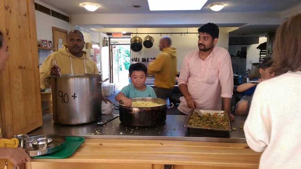 年幼的呂守洵在一間大廚房裡攪拌一大鍋飯。